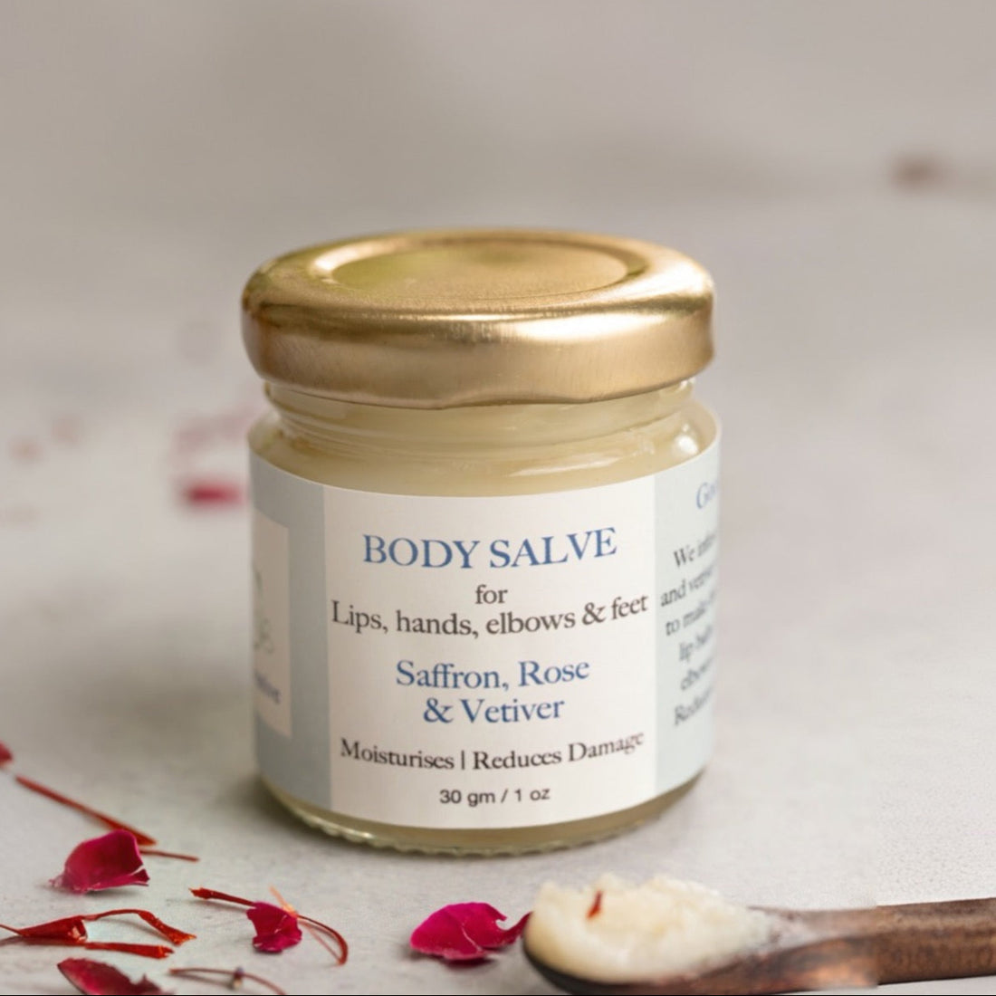 Jar of body salve with saffron, rose, and vetiver on a neutral background